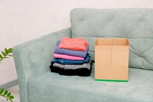 folded clothes next to an empty box on the sofa photo