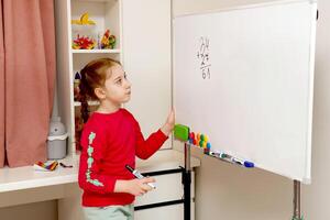 back to school, girl solves house example on blackboard photo