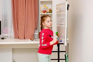 back to school, little girl solves examples at home on the blackboard photo