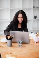 Animated businesswoman participates in a video call, with her laptop on a wood desk in a stylishly minimalist office. photo