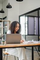 Intensely focused, a businesswoman works diligently on her laptop at a spacious desk in a modern, naturally lit office. photo