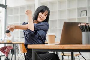 energético joven mujer toma un extensión descanso a su trabajo escritorio, radiante positividad y entusiasmo para bienestar a trabajar. foto