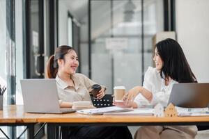 Two female colleagues share a light-hearted moment with coffee during a casual office meeting. photo