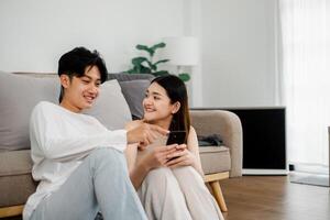 Casual moment captures a couple engaging with content on a smartphone, sharing smiles and a conversation on a comfy couch. photo