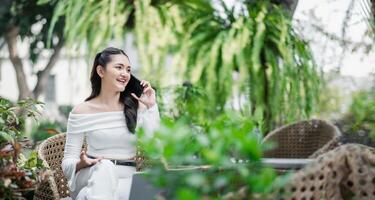 Animated freelancer having a lively phone conversation, comfortably seated in an outdoor patio setting with greenery around. photo