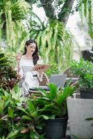 Freelancer deeply engrossed in reading her notes enjoys working outdoors, with a coffee in hand and a laptop nearby in a tranquil garden. photo