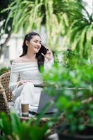 Freelancer having a lively phone conversation, comfortably seated in an outdoor patio setting with greenery around. photo