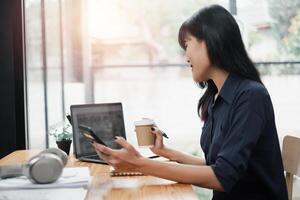 A woman is sitting at a desk with a laptop and a cup of coffee photo