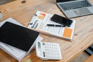 Well-organized work desk displaying a marketing report, tablet, smartphone, calculator, and laptop, ready for business analysis. photo