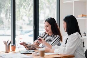 sonriente profesionales comprometido en un colaborativo discusión con un computadora portátil, compartiendo ideas en un moderno oficina espacio. foto