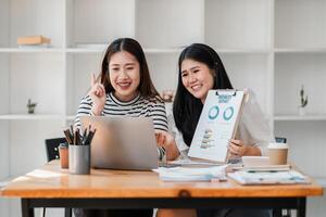 Enthusiastic female team members sharing insights from a business report during a conference call in a modern workspace. photo