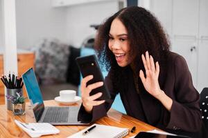 alegre mujer de negocios expresando emoción mientras mirando a su teléfono inteligente, posiblemente celebrando un exitoso acuerdo o positivo actualizar. foto