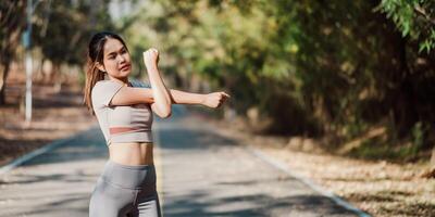 Young woman in fitness attire doing arm stretches before starting her workout on a scenic outdoor trail. photo
