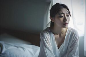 Asian girl feeling sad and lonely in the bedroom under dim light photo