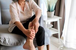 Elder woman feeling leg pain. Concept of leg pain. photo