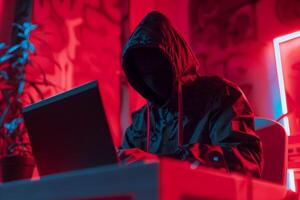 Fashionable anonymous hacker typing computer laptop. Cybercrime, cyberattack, dark web concept. photo