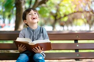 Cute little boy reading holy bible book at countryside photo