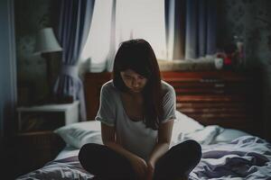 Asian girl feeling sad and lonely in the bedroom under dim light photo