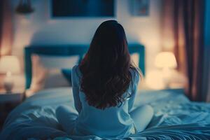 Back view of Asian girl feeling sad and lonely in the bedroom under dim light photo