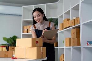 Woman entrepreneur prepare parcel box and check online order on laptop computer for commercial checking delivery. online marketing, packing box, SME seller. startup business concept photo