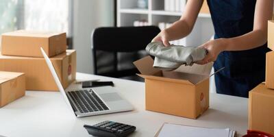 Asian business owner working at home with packing box of her online store prepare to deliver product to customers, sme business ideas online concept photo