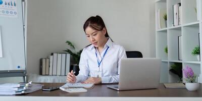 Young business woman asian or employee accounting bookkeeping documents checking financial data or marketing report working in office with laptop. Paperwork management photo