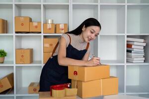 Woman asian in an online store check the customer address and package information on box. Online shopping concept photo