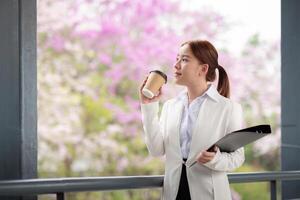 Young Asian business woman entrepreneur, professional manager holding Document file standing on the street in city photo