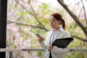 Young Asian business woman entrepreneur, professional manager holding Document file standing on the street in city photo