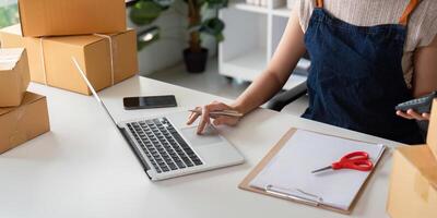 Woman in an online store check the customer address and package information on the laptop. Online shopping concept photo