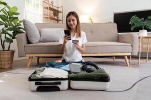 Asian woman using credit card booking flight tickets and hotel at home. Planning a trip and online booking, Summer vacation concept photo