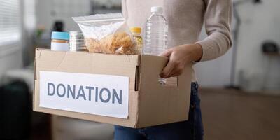 Woman volunteer holding food donation box at home photo