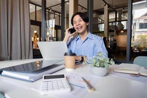 Business man asian discussing a new project with his client on the phone. business man working on a laptop in office photo