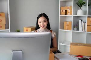 Young business woman asian working online ecommerce shopping at her shop. Young woman sell prepare parcel box of product for deliver to customer. Online selling photo