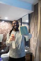 Happy young African American man cleaning the glass in the apartment. Cleaning maintain cleanliness in with towel and spray detergent photo