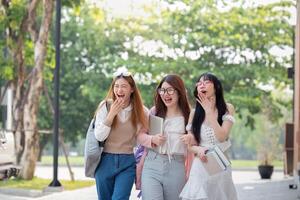 College friends walk to class together. University student in campus talk and have fun outdoors photo