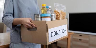 Woman volunteer holding food donation box at home photo