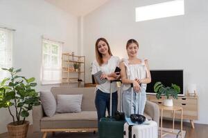 amigos y viajar. dos asiático joven mujer amigos embalaje un viaje bolso antes de yendo en fiesta foto