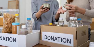 voluntario preparando gratis productos alimenticios raciones para pobre gente. caridad dos mujer de el comunidad trabajo juntos. concepto de dando y humanitario ayuda foto