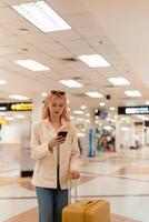 un mujer asiático caminando en un aeropuerto. móvil, maleta y viaje con un joven hembra en un internacional viaje para trabajo o viaje foto