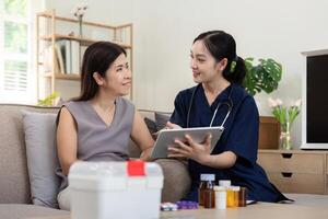 Female caregiver showing medical test result explaining prescription using digital tablet app visit senior woman patient at home sitting on sofa. Elderly people healthcare tech concept photo