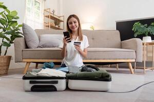 Asian woman using credit card booking flight tickets and hotel at home. Planning a trip and online booking, Summer vacation concept photo