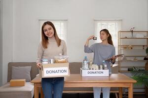 Woman with charity box and group of volunteers at assistance center. Charity, donation, and volunteering concept photo