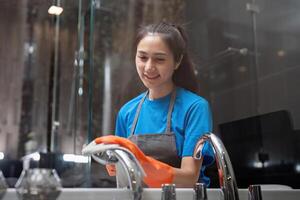 Professional cleaning service company employee in rubber gloves cleaning and detergent spray in bathroom photo