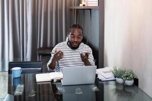 Professional man working remote from home with technology. African American male has a business meeting on an audio call phone photo