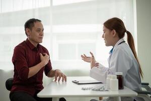Doctor young woman white coat giving medical consultation to male elderly mature patient, discussing healthcare treatment or health test results at hospital photo
