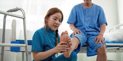 Physical therapist Asian woman, doing leg physiotherapy for elderly man to treat osteoarthritis and nerve pain in the leg to nursing at home and health care concept photo