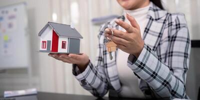 Real estate agent with house model and key photo