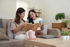 contento mayor madre con adulto hija sentado en sofá y participación tazas con café o té a hogar. disfrutar familia concepto foto