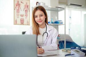 Female doctor working on laptop at office desk at in health clinic or hospital photo